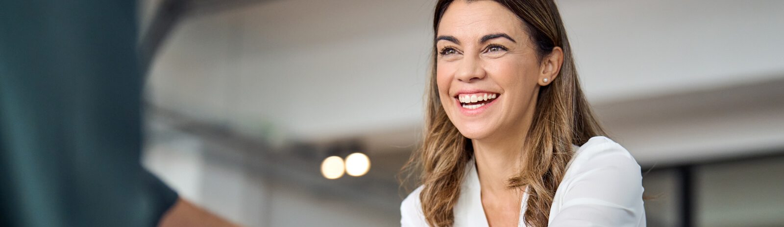 Happy mid aged business woman shaking hands in office.